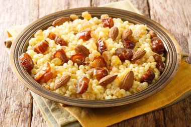 Mesfouf  super-soft steamed sweet buttery couscous with dried fruits and nuts close-up in a plate on the table. horizonta