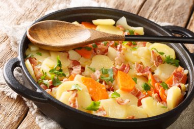 Domuz pastırmalı, soğanlı ve havuçlu güveçte patates kızartma tavasında. yatay