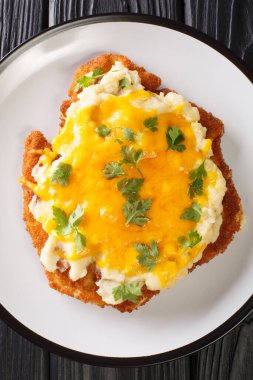 Teesside Chicken Parmo üzerine beyaz bechamel sosu ve masanın üzerindeki tabakta yakın plan çedar peyniri ile eklenmiş tavuk filetosundan yapılmıştır. Yukarıdan dikey üst görünüm