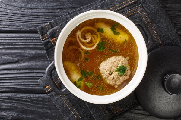 Delicious Viennese rindsuppe soup based on beef broth with dumplings close-up in a saucepan on the table. horizontal top view from abov — Stock Image Delicious Viennese Rindsuppe Soup Based Beef Broth Dumplings Close Saucepan Royalty Free Stock Images