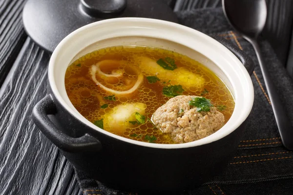 Delicious Viennese rindsuppe soup based on beef broth with dumplings close-up in a saucepan on the table. horizonta — Stock Image Delicious Viennese Rindsuppe Soup Based Beef Broth Dumplings Close Saucepan Stock Picture