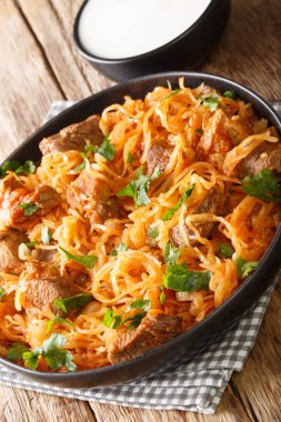 Macar Szegedin Gulash, masada tabakta harika bir şekilde zengin kırmızı biber çorbası ile yavaş kaynayan, sulu domuz eti, soğan ve lahana turşusu sunuyor. dikey