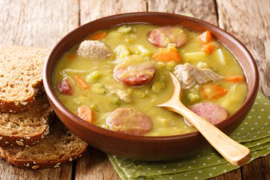 Sebzeli yeşil bezelye çorbası, sosis ve yakın plan domuz eti masanın üstünde. yatay