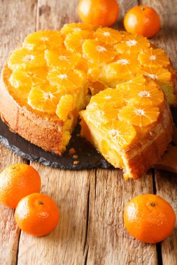 Masadaki tahtaya yakın plan dilimlenmiş mandalina turtası. dikey