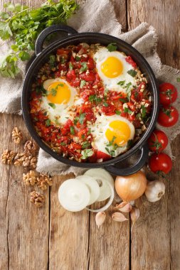 Masadaki tavada domatesli, soğanlı ve cevizli Gürcü kahvaltısı yumurtası. yukarıdan dikey üst görünüm