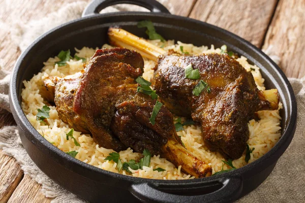 Popular Yemeni baked lamb shank served with basmati rice close-up in a frying pan on the table. horizonta