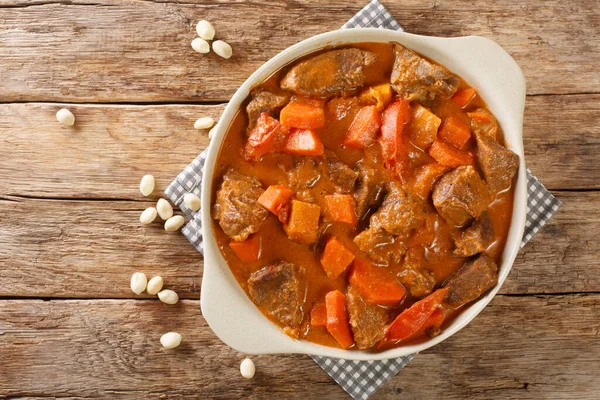 Senegalese stew of beef in peanut sauce with vegetables close-up in a dish on the table. horizontal top view from abov