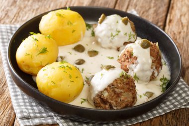 Lezzetli Alman Konigsberger Klopse köfteleri kapari soslu ve masada yakın plan haşlanmış patatesle servis ediliyor. yatay