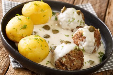 Konigsberger Klopse kapari ile soslu Alman Köfteleri masanın üzerinde yakın plan bir tabakta. Yatay