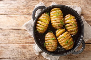 İsveç usulü Hasselback patatesleri masanın üstünde tavaya yakın plan. Yukarıdan yatay üst görünüm