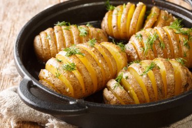 İsveç usulü Hasselback patatesleri masanın üstünde tavaya yakın plan. Yatay