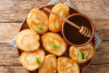 Tatlı Tiganitler geleneksel Yunan krepleri. Masanın üzerinde bal resmi var. Yukarıda yatay üst görünüm