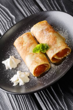Palatschinken Austrian crepes with apricot jam close-up in a plate on the table. vertica