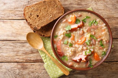 Homemade Ricet barley and bean soup with smoked meat and vegetables close-up in a bowl on the table. horizontal top view from abov clipart