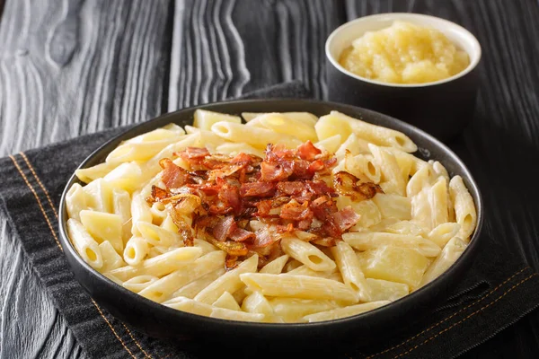 Authentic Swiss alplermagronen is pasta with potatoes and cheese and fried onions, bacon close-up in a plate on the table. horizonta