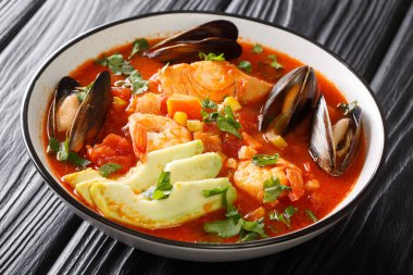 Morina, karides, midye, sebze ve avokado karışımlı Sopa de Mariscos deniz ürünleri çorbası masanın üstünde. Yatay