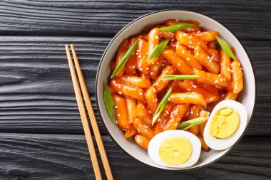 Hot and spicy rice cake Tteokbokki recipe close-up in a bowl on the table. horizontal top view from abov clipart