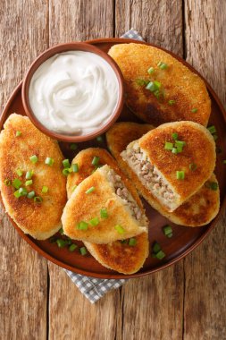 Ekşi kremayla servis edilen, masada yakın plan bir tabakta servis edilen patatesli sandviç. Yukarıdan dikey üst görünüm