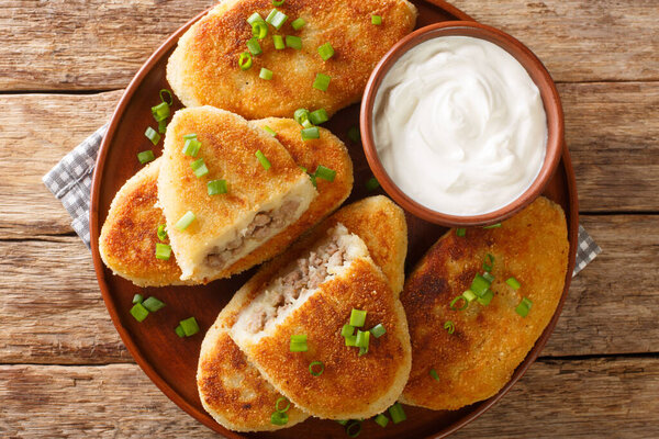 Zrazy potato pancakes with meat filling with sour cream close-up in a plate on the table. horizontal top view from abov