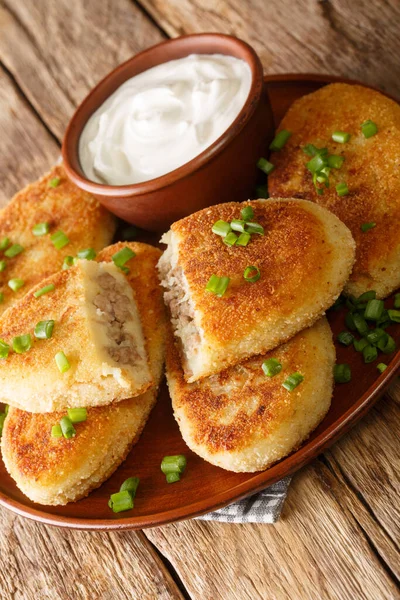 Ekşi kremayla servis edilen, masada yakın plan bir tabakta servis edilen patatesli sandviç. Dikey