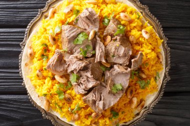 Mansaf is a dish of rice, lamb, and a dry yoghurt made into a sauce called jameed closeup in the plate on the table. horizontal top view from abov clipart