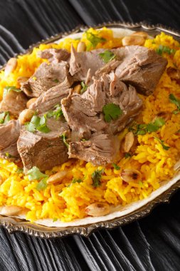 Mansaf, yoğurt sosunda pişirilen geleneksel bir Arap kuzu etidir. Masanın üzerindeki tabakta yakın plan pirinç vardır. Dikey