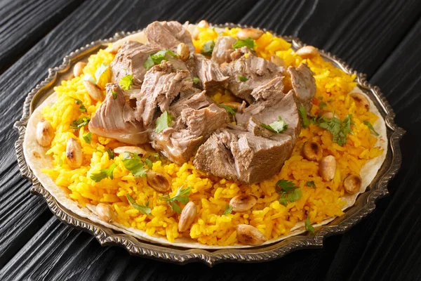 Mansaf a feast dish of lamb in yogurt sauce atop flatbread and a bed of rice, is known as the national dish of Jordan closeup in the plate on the table. horizonta