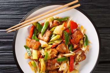 İki kere pişirilmiş domuz hui guo rou Szechuan Pork Stir Fry ahşap masanın üzerindeki tabağa yakın çekim. Yukarıdan yatay üst görünüm
