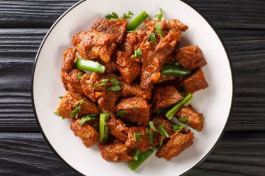Tibs is an Ethiopian dish consisting of stir-fried meat and vegetables closeup in the plate on the table. Horizontal top view from abov