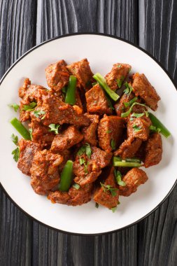 Tibs is a popular Ethiopian dish of sauteed beef flavored with niter kibbeh and berbere closeup in the plate on the table. Vertical top view from abov