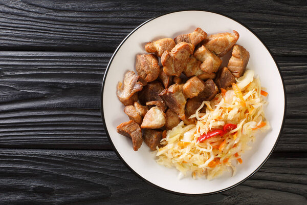 Griot is a dish in Haitian cuisine it consists of pork shoulder marinated in citrus, which is braised and then fried close-up in a plate on the table. Horizontal top view from abov