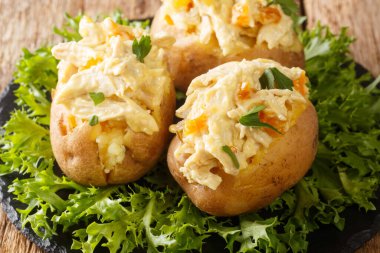 Taçlandırılmış tavuk salatasıyla fırında patates, soğuk pişirilmiş tavuk eti, otlar ve baharatların bir karışımıdır ve masanın üzerindeki tabakta kremalı mayonez sosu kapalıdır. Yatay