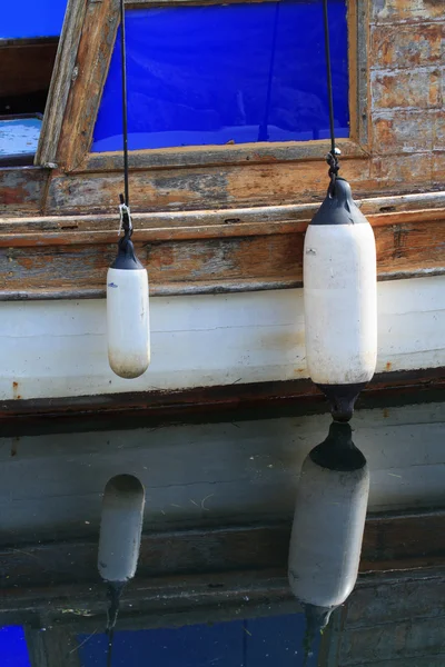 Dois pára-lamas em um velho barco com reflexão na água — Fotografia de Stock