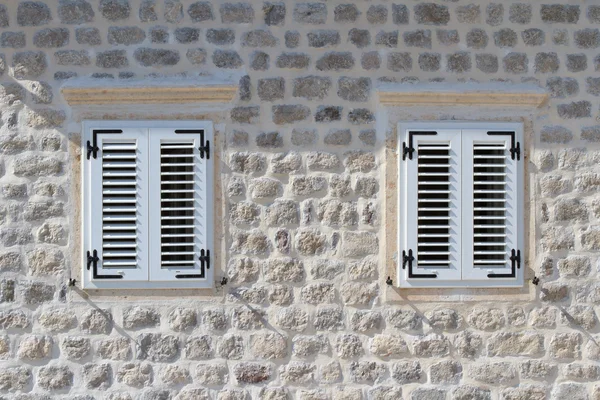 Duas janelas fechadas na parede de pedra da casa — Fotografia de Stock