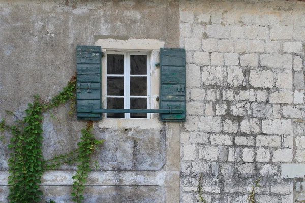 Otevřené okno s zelenými okenicemi na staré kamenné zdi — Stock fotografie