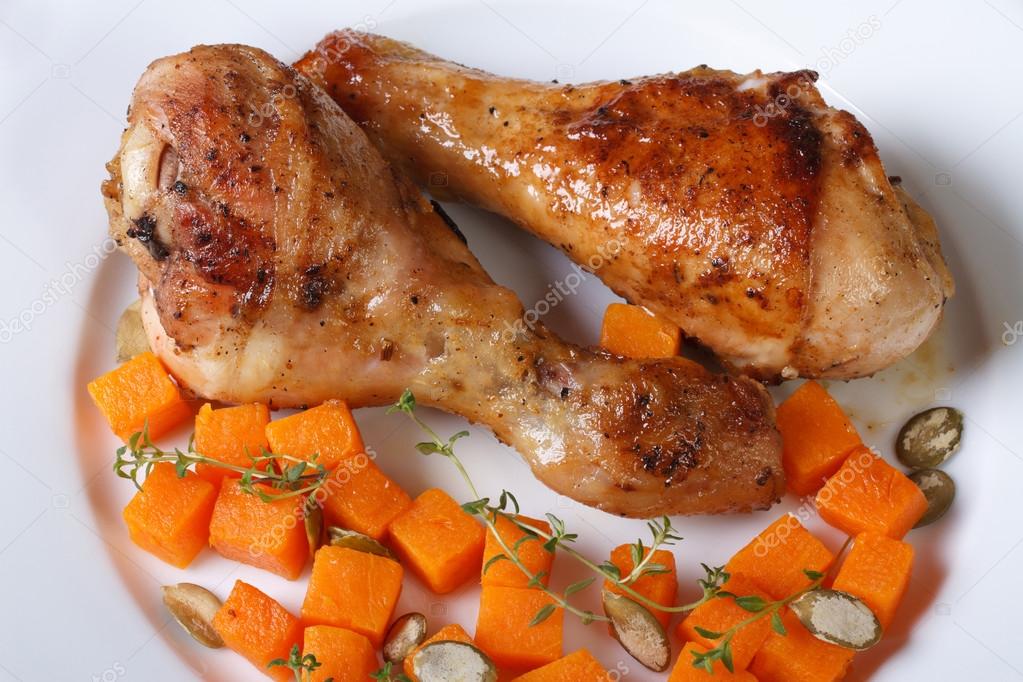 Roasted chicken drumsticks with a pumpkin, view from above