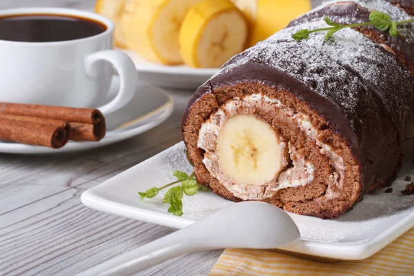 Chocolate roll with banana and coffee close-up. horizontal — Stock Photo, Image