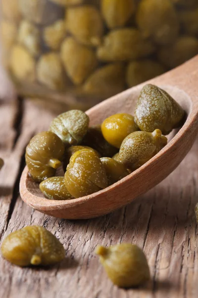 Capers in a spoon closeup on a background of a jar vertical — Stock Photo, Image