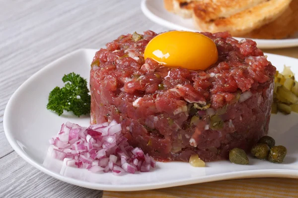 Carne tártara com gema de ovo, cebolas e alcaparras close-up — Fotografia de Stock