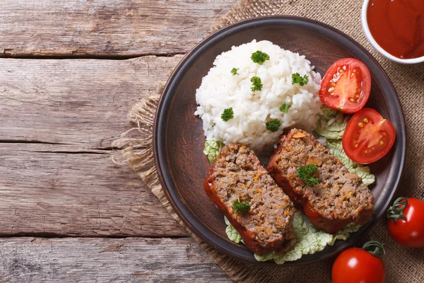Pieces of meat loaf and rice, vegetables on a plate top view — Stock Photo, Image