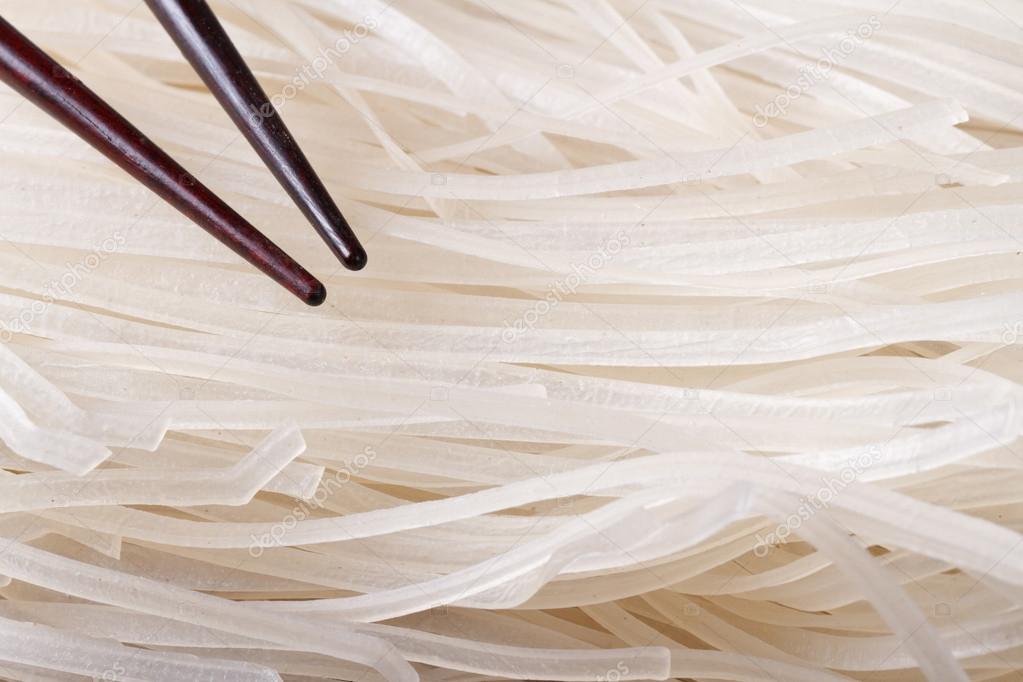 Dry rice noodles with chopsticks macro.