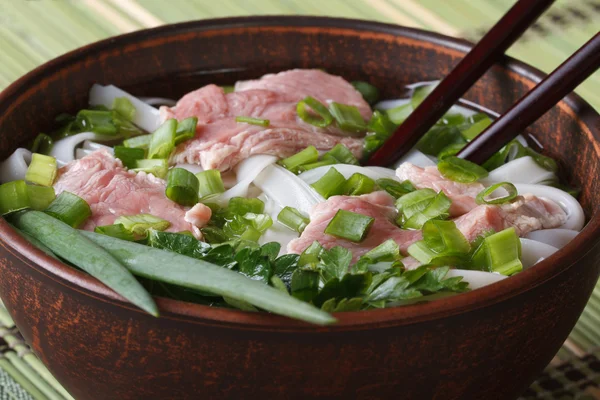 Soupe asiatique au bœuf, nouilles de riz et herbes fraîches dans un bol . — Photo