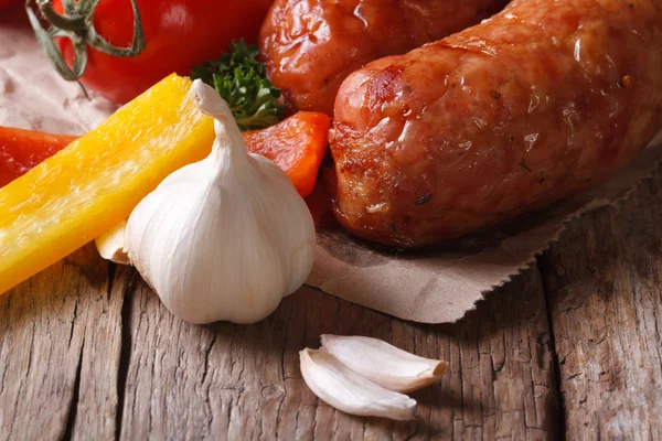 Salsicce grigliate e verdure fresche da vicino su un vecchio tavolo — Foto Stock