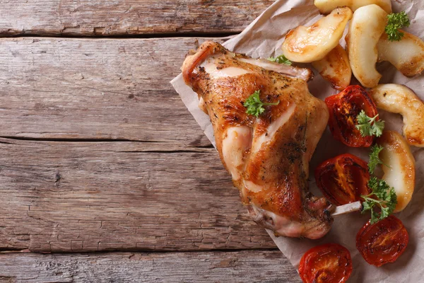 Tasty roast leg of rabbit with apples and tomatoes top view — Stock Photo, Image