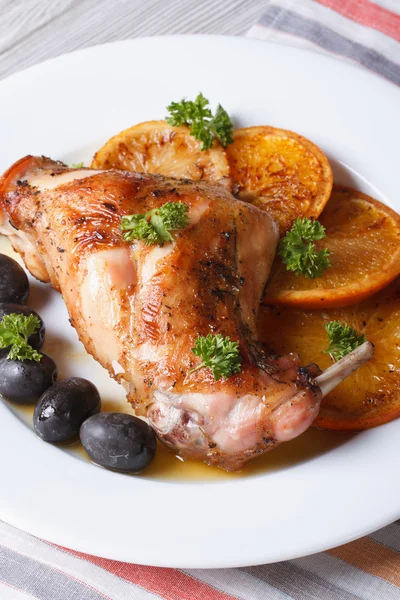 Roasted rabbit leg with oranges and olives on the plate. vertica — Stock Photo, Image