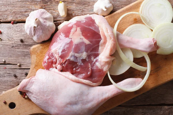 Raw duck legs on a cutting board with onion and garlic, top view — Stock Photo, Image