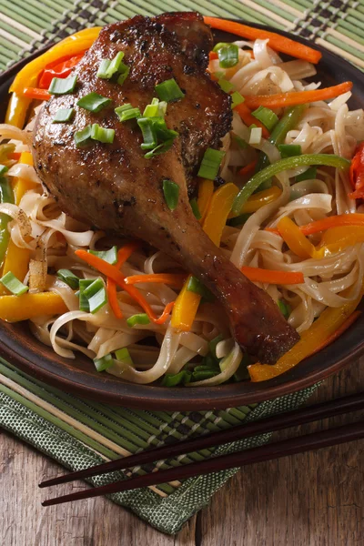 Roasted duck leg with rice noodles and vegetables closeup. Verti — Stock Photo, Image