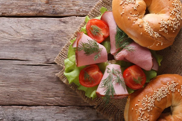 Bagel with ham on an old wooden table top view horizontal — Stock Photo, Image