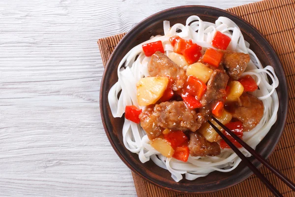 pork meat in sweet and sour sauce with rice noodles top view