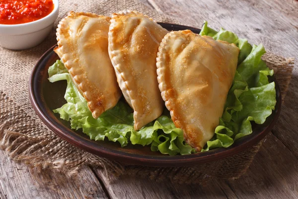Pies empanadas on a plate with lettuce and sauce, horizontal — Stock Photo, Image